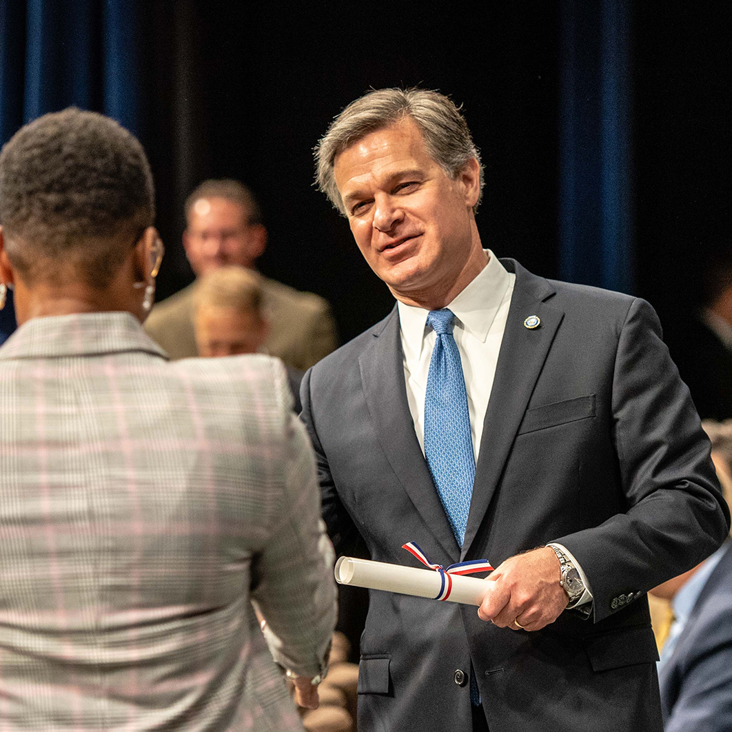 Director of FBI shaking the hand of an FBI employee while handing them a certificate