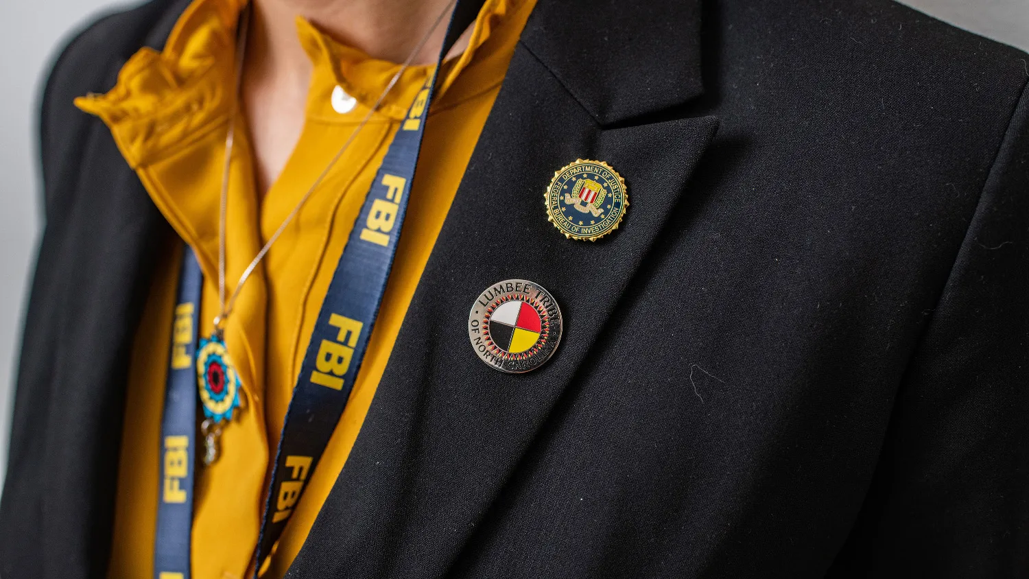 Two pins attached to the lapel of a blazer represent the FBI and the Lumbee Tribe of North Carolina
